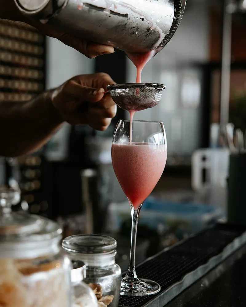 Bartender pouring a pink cocktail at Times of India