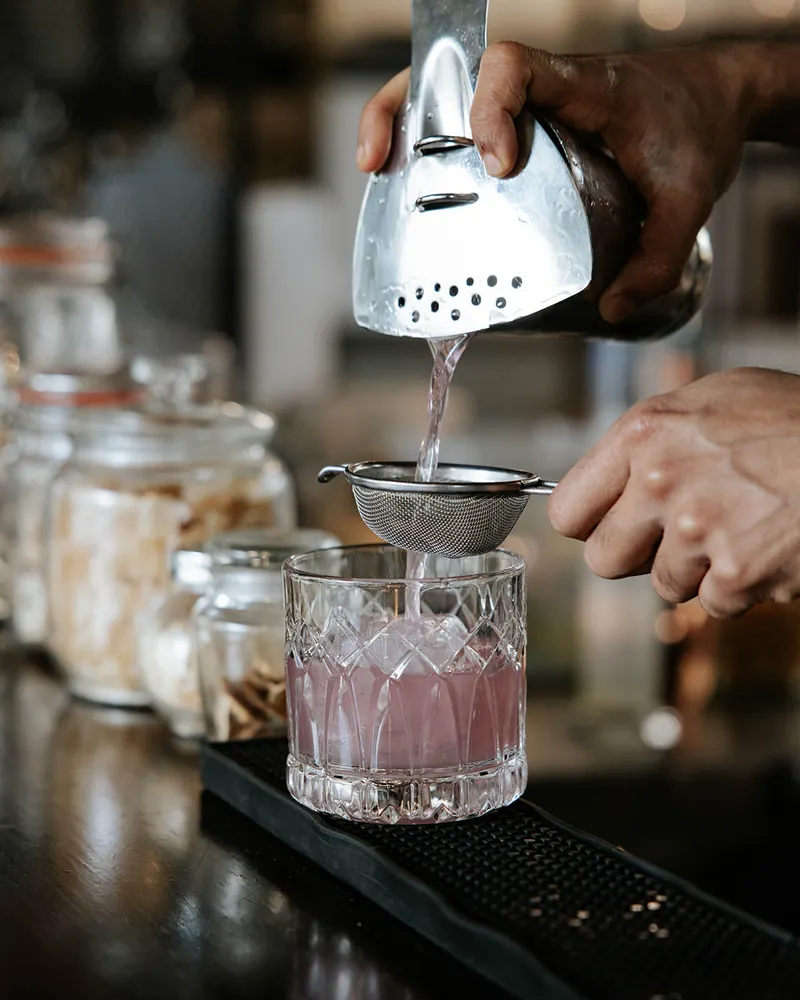 Bartender straining a freshly made cocktail at Times of India