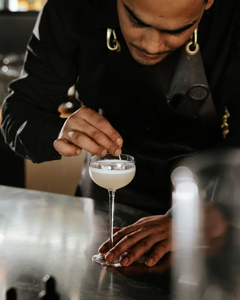 Bartender finishing a cocktail in a coupe glass at Times of India